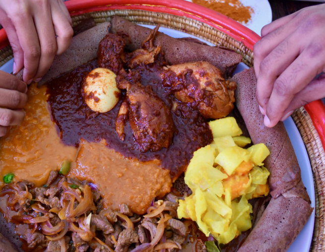 Traditional Ethiopian or Eritrean food featuring injera and doro wat served on a communal platter