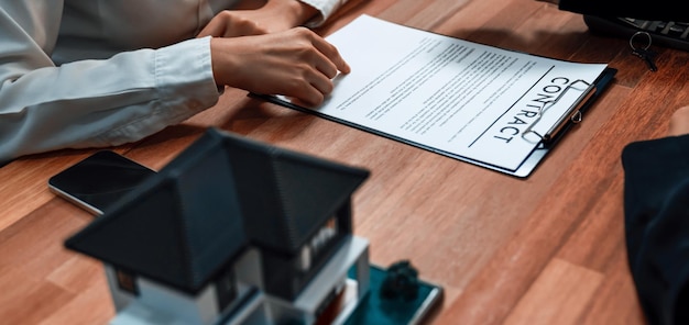 Real estate agent and client reviewing physical contract documents on a wooden desk.