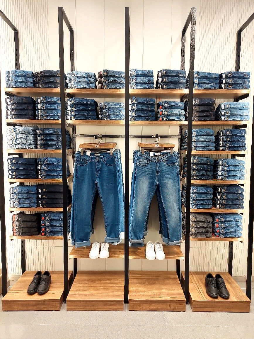 Denim jeans displayed neatly on retail shelving inside a modern clothing store.