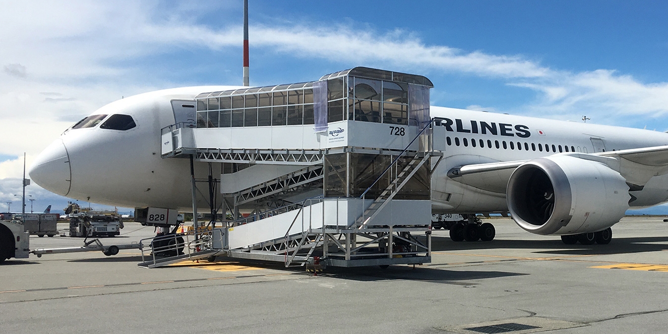 Commercial aviation support vehicles parked near a terminal boarding gate.