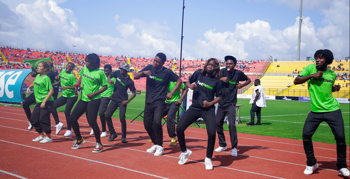 Performers and dancers energizing the crowd on the running track during a betPawa Premier League match at Baba Yara Stadium in Kumasi, Ghana.