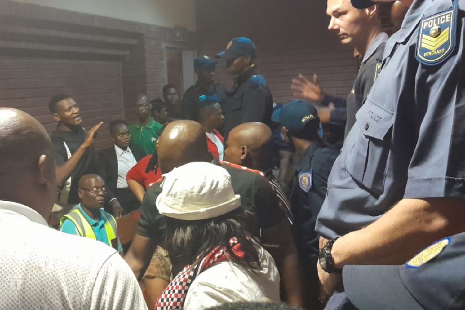 Community members gathering outside the municipal court during suspect hearings in South Africa.