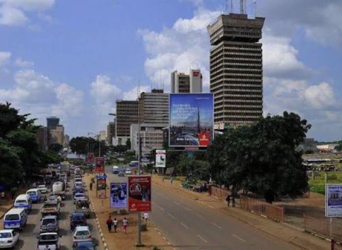 Busy street scene in downtown Lusaka with commercial traffic and pedestrians.