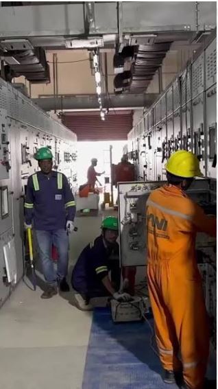 Electrician inspecting power control panels wearing safety gear.
