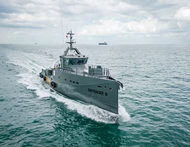 Gray military naval ship cruising across the ocean waves during daytime.