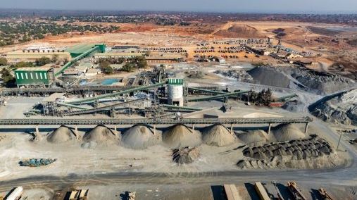 Aerial view of a large-scale industrial mining and mineral processing plant featuring conveyor belts, storage silos, and aggregate stockpiles.
