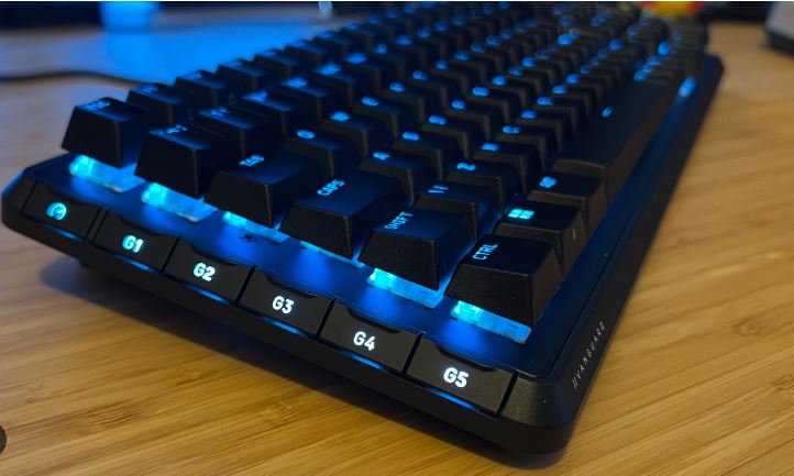 RGB mechanical keyboard glowing with colorful backlight inside a dark room.
