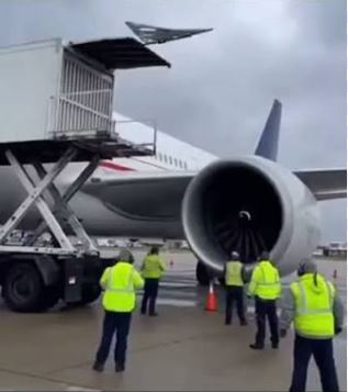 Ground staff inspecting the turbine engine of a commercial jet.