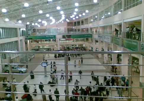 Passageway inside a bustling modern airport terminal building.