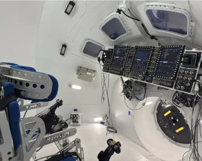 Close-up of an astronaut helmet visor reflecting instrument lights.