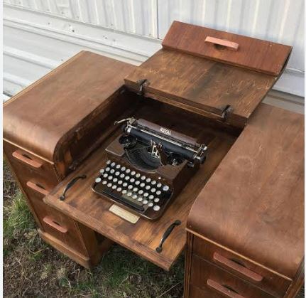 Vintage mechanical typewriter resting on an antique wooden desk.